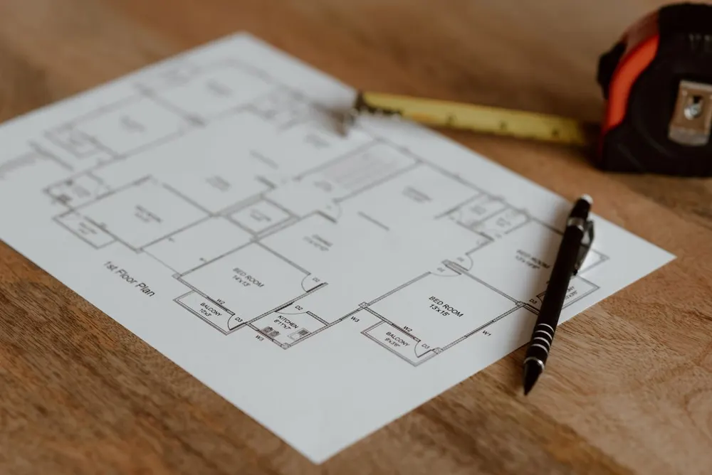 Grundrissplan mit Zollstock und Stift auf einem Holztisch